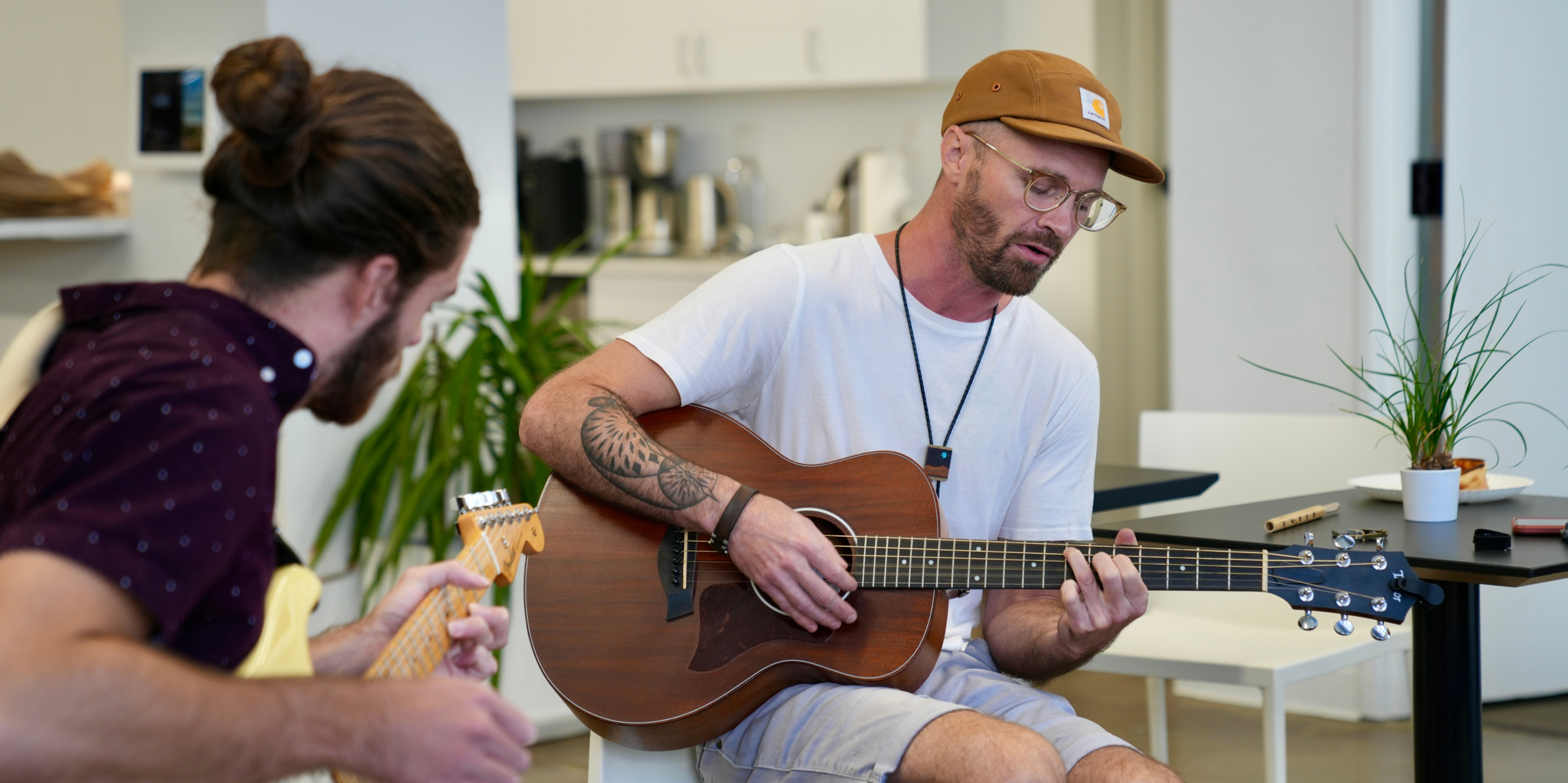 Benjamin and Stevey, two Kaura artists, playing instruments in an office environment.