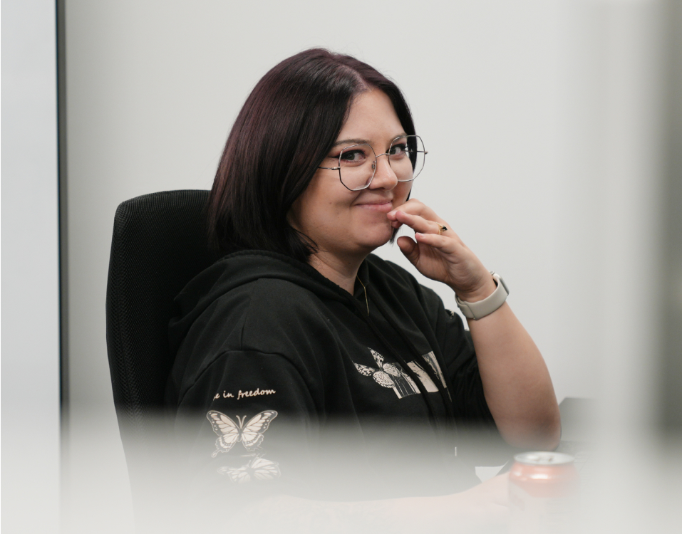 Bri, a Kaura team member, wearing glasses seated at a desk.