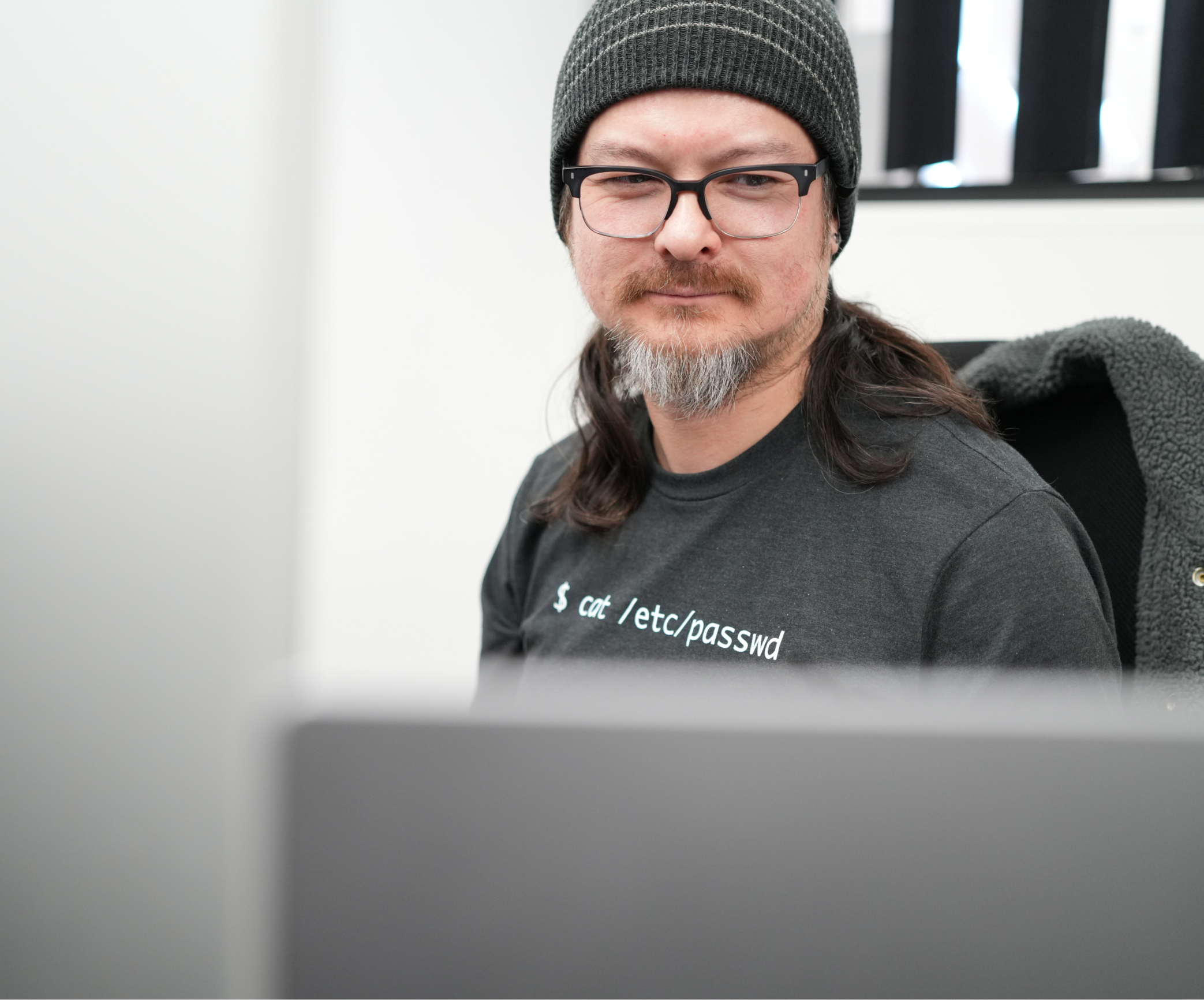 Don, a Kaura team member, wearing a black shirt and beanie hat seated at a desk.