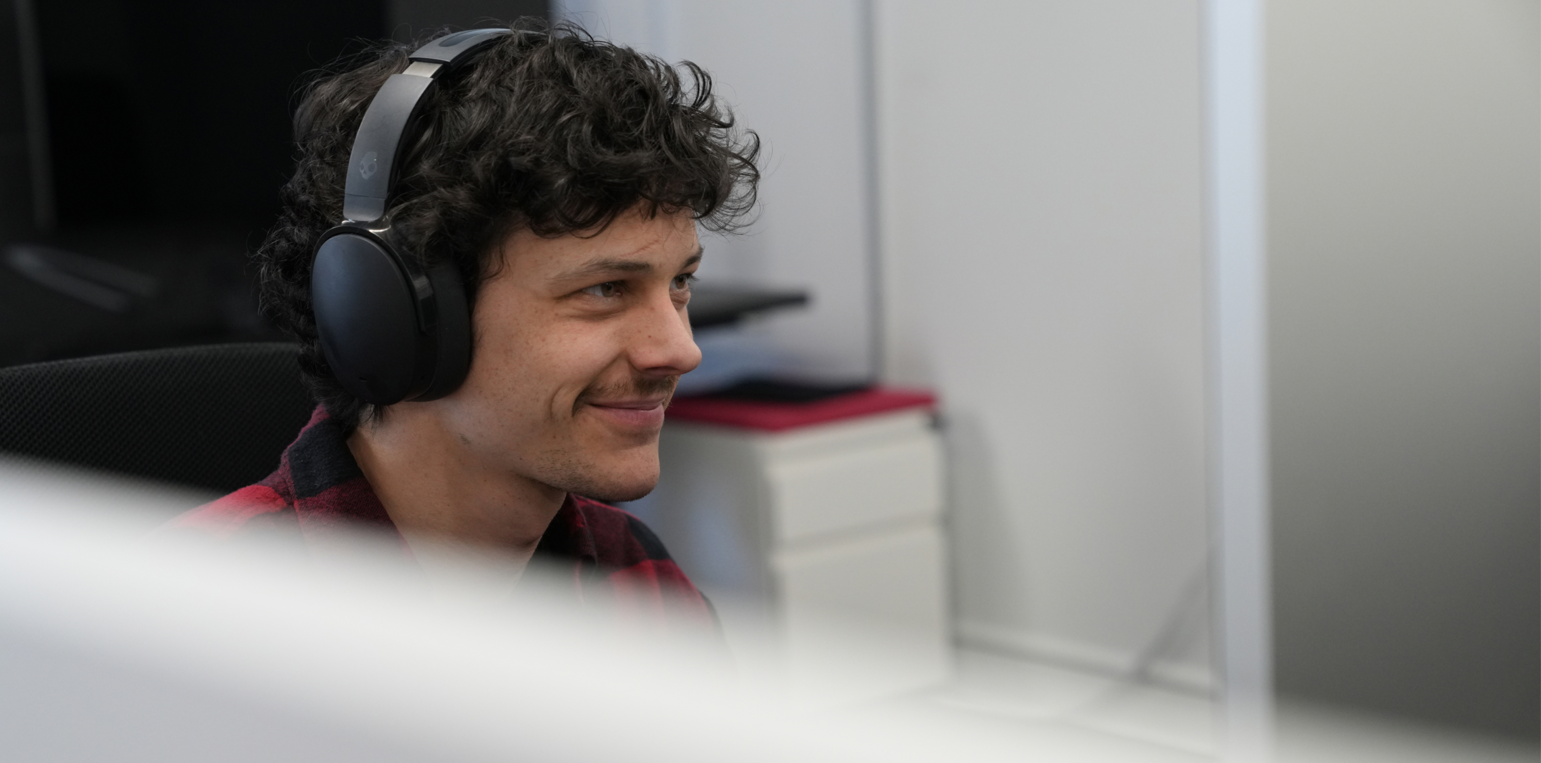 Jake, a Kaura team member, wearing headphones seated at a desk.